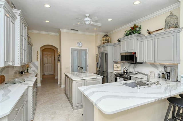 kitchen with sink, gray cabinetry, a center island with sink, a kitchen breakfast bar, and stainless steel appliances