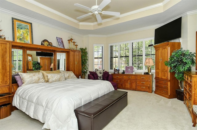 carpeted bedroom featuring multiple windows, a tray ceiling, crown molding, and ceiling fan