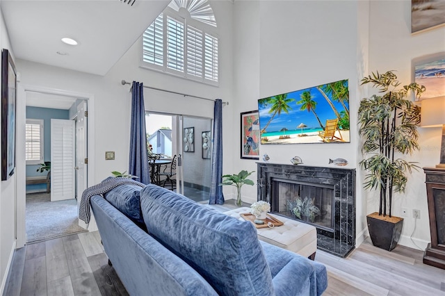 living room featuring a fireplace, a wealth of natural light, wood-type flooring, and a high ceiling