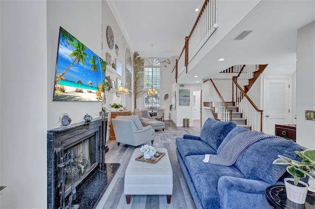 living room featuring a fireplace, a towering ceiling, wood-type flooring, and a notable chandelier