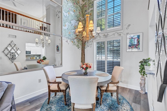 dining room with a towering ceiling, a chandelier, and hardwood / wood-style floors