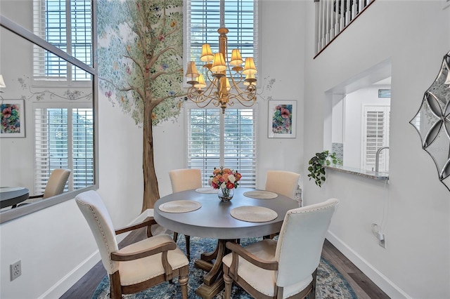 dining room with wood-type flooring, plenty of natural light, and a towering ceiling