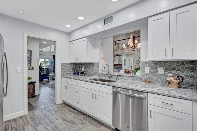 kitchen featuring sink, light stone counters, light hardwood / wood-style flooring, appliances with stainless steel finishes, and white cabinets