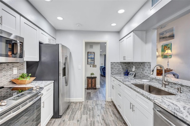 kitchen featuring white cabinetry, sink, stainless steel appliances, and light stone countertops