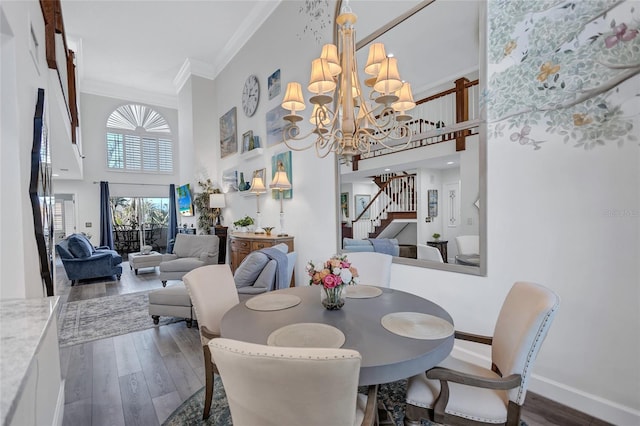 dining room with dark wood-type flooring, ornamental molding, a chandelier, and a high ceiling