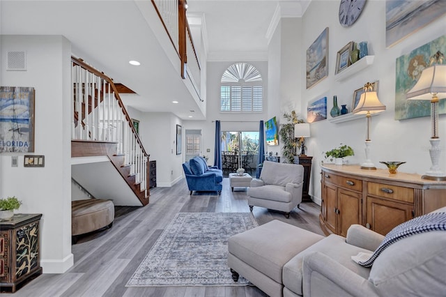 living room with crown molding, light hardwood / wood-style flooring, and a high ceiling