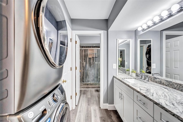 bathroom featuring vanity, stacked washer / drying machine, wood-type flooring, and an enclosed shower