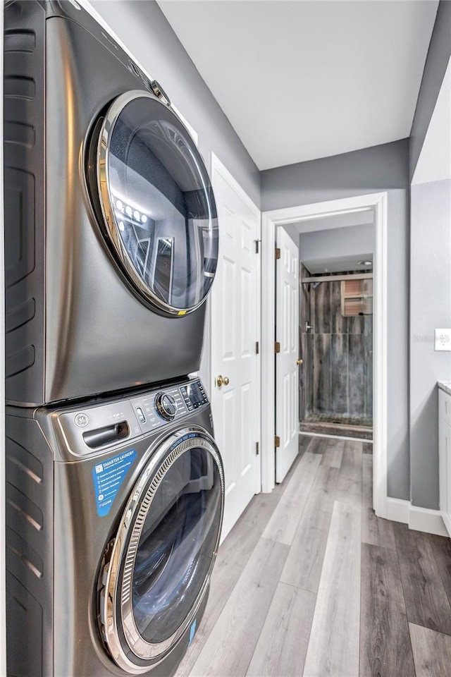 laundry area featuring light wood-type flooring and stacked washer / dryer