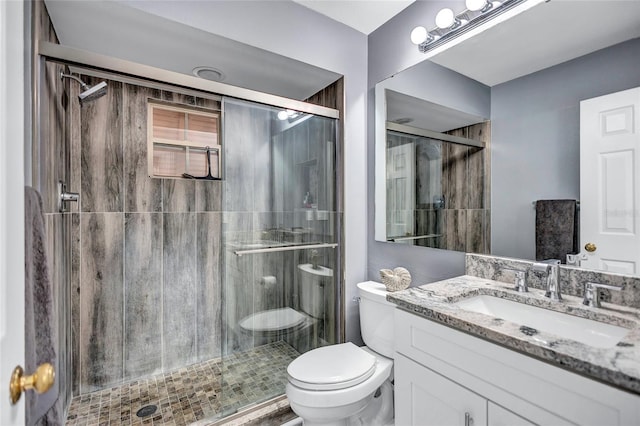 bathroom with vanity, toilet, and a shower with door