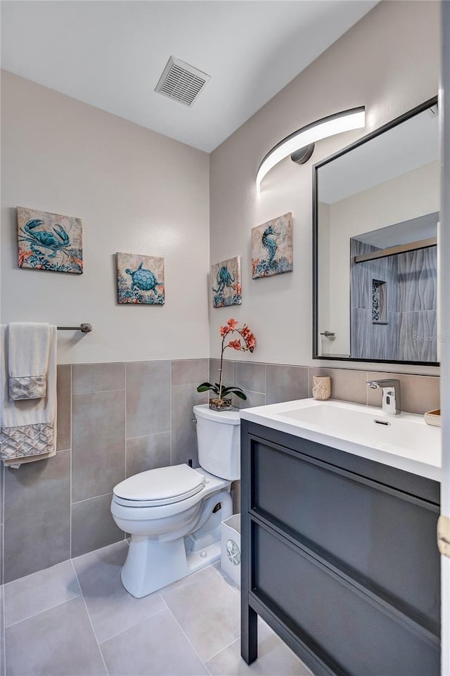 bathroom with vanity, tile walls, tile patterned floors, and toilet