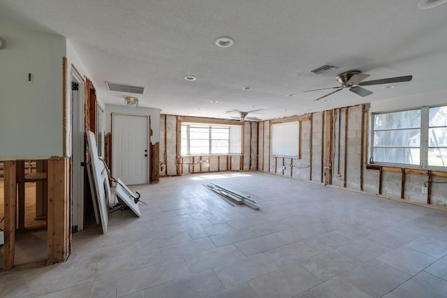 interior space featuring ceiling fan, a textured ceiling, and visible vents