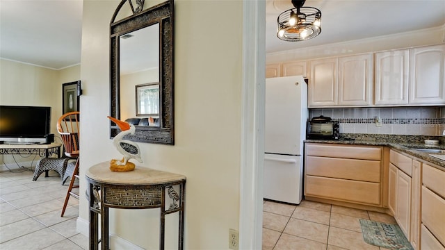 kitchen with tasteful backsplash, light tile patterned flooring, white fridge, and light brown cabinetry