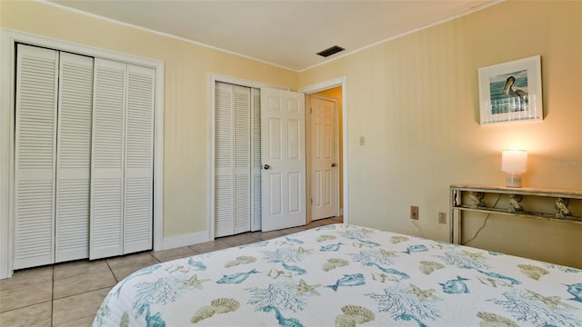 tiled bedroom featuring crown molding and two closets