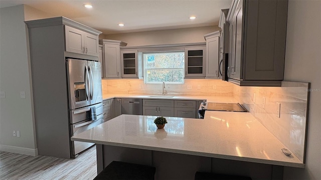 kitchen with sink, gray cabinetry, appliances with stainless steel finishes, kitchen peninsula, and decorative backsplash