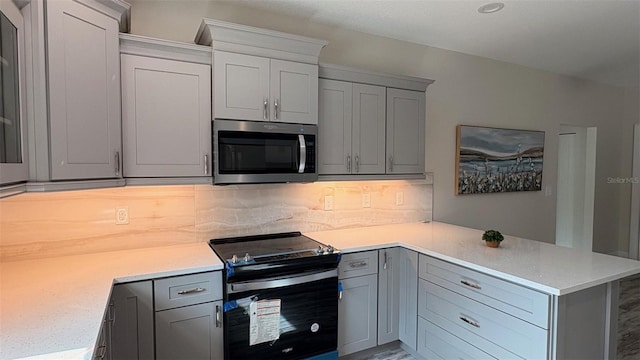 kitchen featuring tasteful backsplash, electric range oven, gray cabinetry, and kitchen peninsula