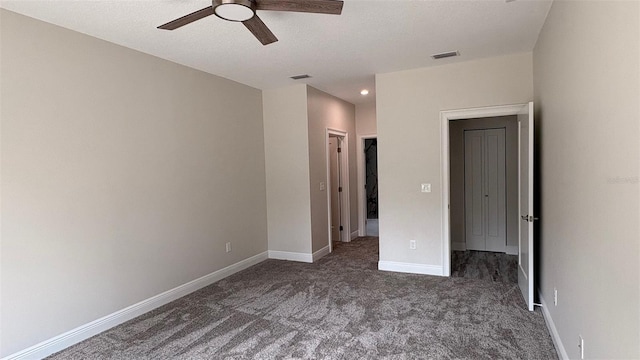 unfurnished bedroom with ceiling fan and dark carpet