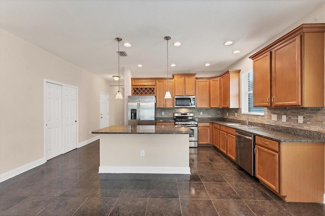 kitchen featuring pendant lighting, sink, appliances with stainless steel finishes, a center island, and tasteful backsplash