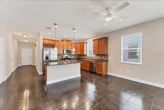 kitchen featuring ceiling fan, hanging light fixtures, backsplash, stainless steel appliances, and a center island