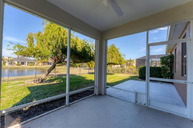 unfurnished sunroom featuring ceiling fan and a water view