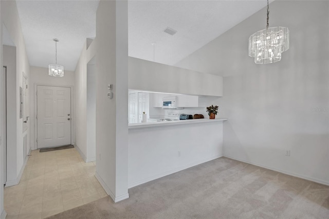 interior space with pendant lighting, a high ceiling, range, light carpet, and an inviting chandelier