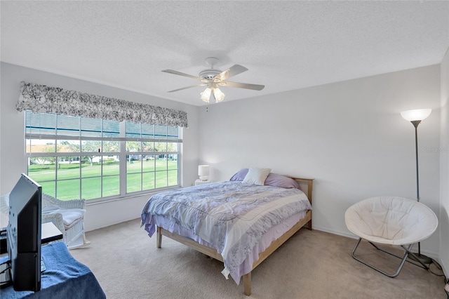 bedroom with ceiling fan, light carpet, and a textured ceiling