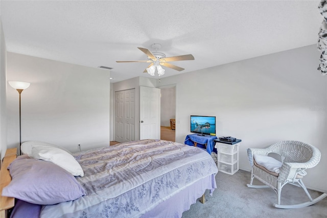 bedroom with ceiling fan, carpet floors, a closet, and a textured ceiling