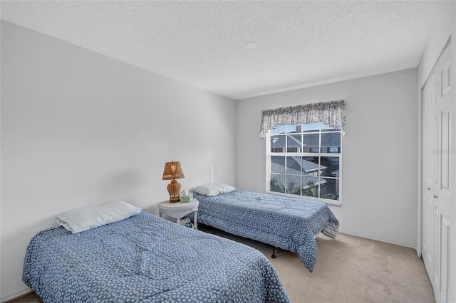 bedroom featuring light colored carpet, a closet, and a textured ceiling