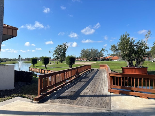 surrounding community with a water view and a lawn