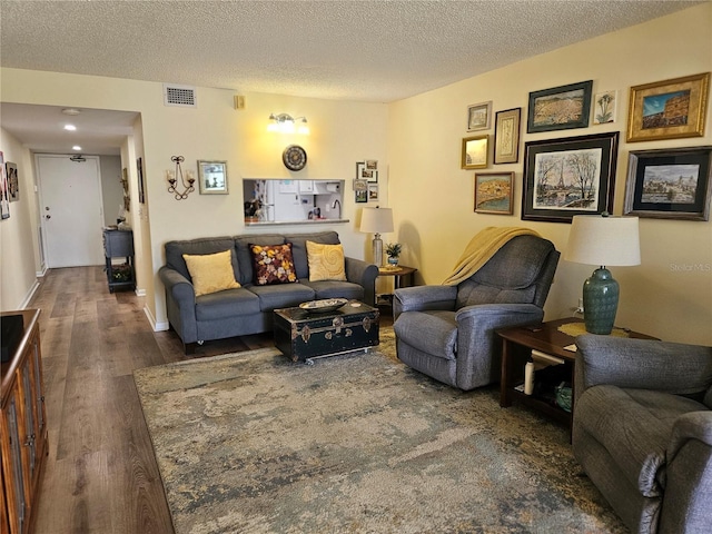 living room with dark wood-type flooring and a textured ceiling