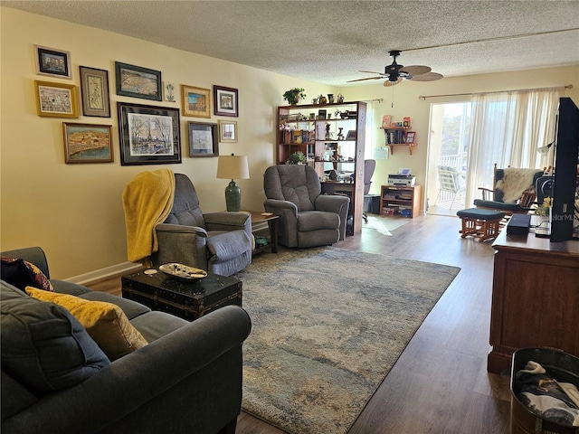 living area with a ceiling fan, a textured ceiling, and wood finished floors