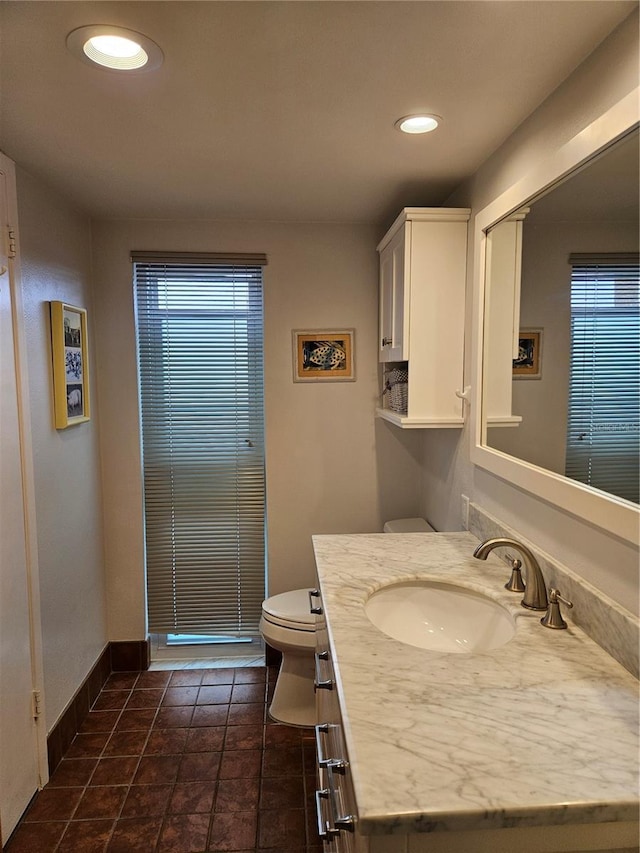 half bathroom featuring baseboards, toilet, tile patterned flooring, vanity, and recessed lighting