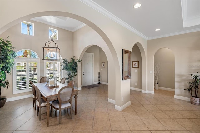 tiled dining space with ornamental molding and an inviting chandelier