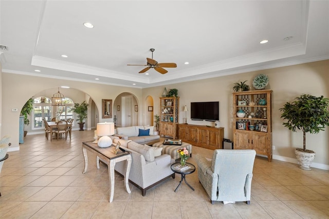 tiled living room featuring a tray ceiling and ornamental molding