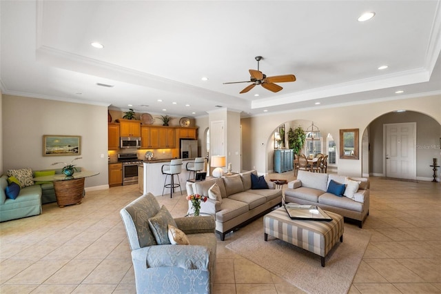 tiled living room with ornamental molding, a raised ceiling, and ceiling fan