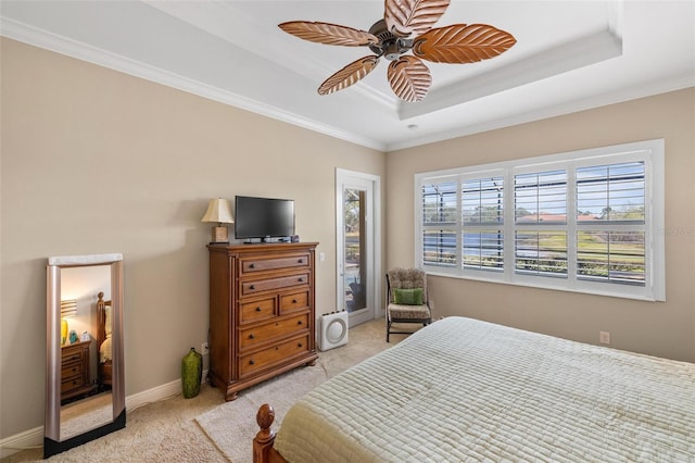 bedroom with crown molding, light colored carpet, a tray ceiling, and ceiling fan