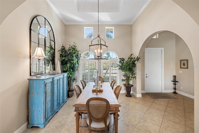 tiled dining room featuring ornamental molding, a healthy amount of sunlight, an inviting chandelier, and a tray ceiling