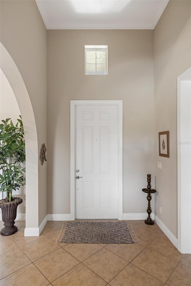 foyer with light tile patterned floors and ornamental molding