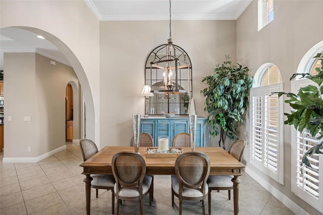 dining area with crown molding, a towering ceiling, an inviting chandelier, and light tile patterned floors