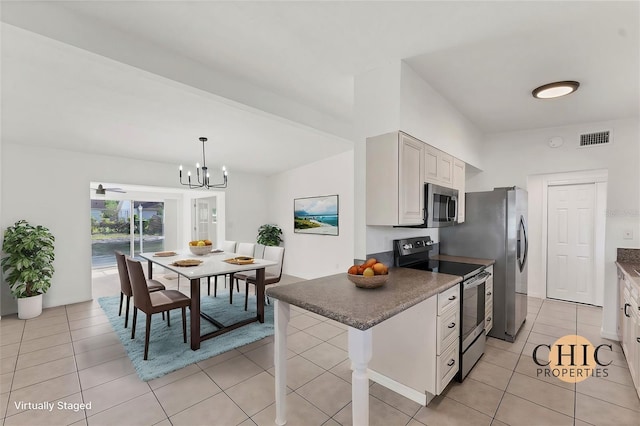 kitchen featuring white cabinetry, appliances with stainless steel finishes, a kitchen bar, and decorative light fixtures