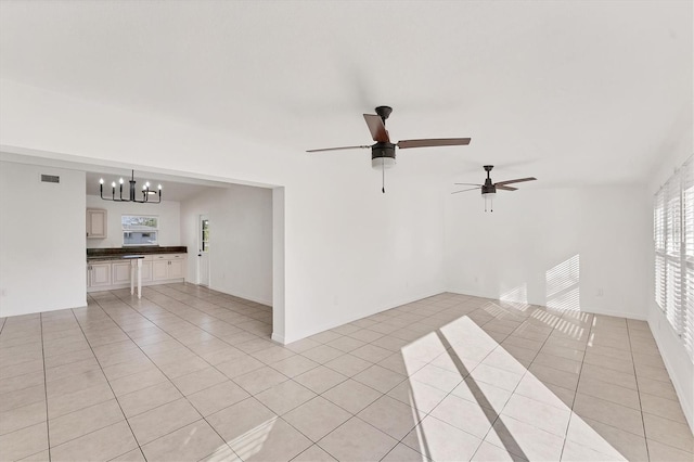 unfurnished living room featuring ceiling fan with notable chandelier and light tile patterned floors