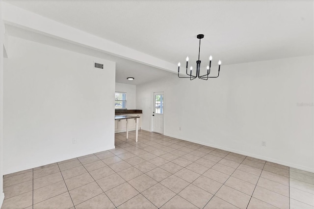 tiled spare room featuring an inviting chandelier