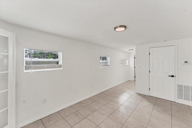 unfurnished room with plenty of natural light and light tile patterned floors