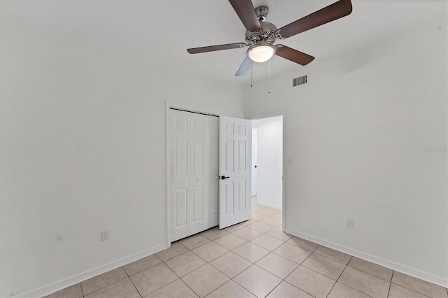 interior space with light tile patterned flooring, ceiling fan, and a closet