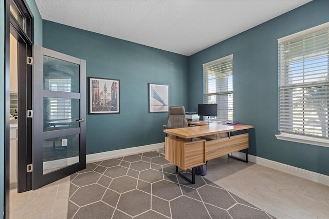 office space with a wealth of natural light, tile patterned floors, and a textured ceiling