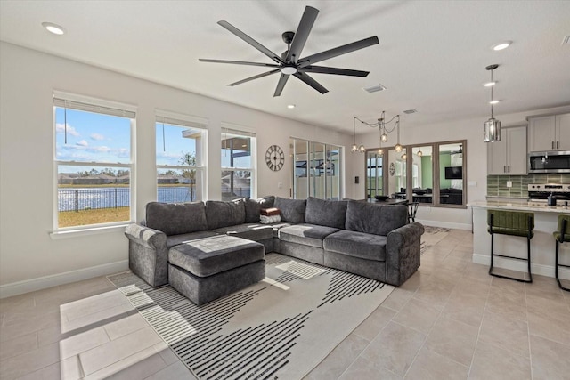 living room with light tile patterned floors, ceiling fan, and a water view