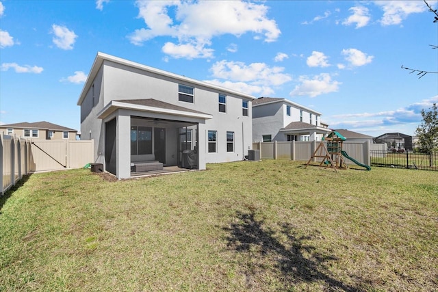 rear view of house featuring a playground, a sunroom, and a lawn