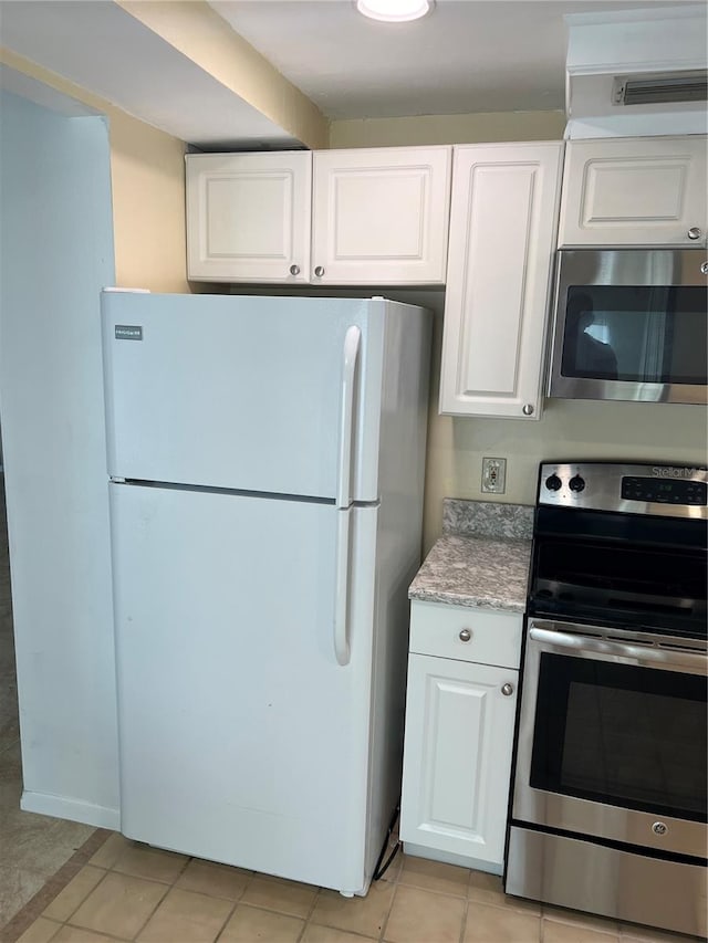 kitchen with light tile patterned flooring, appliances with stainless steel finishes, and white cabinets