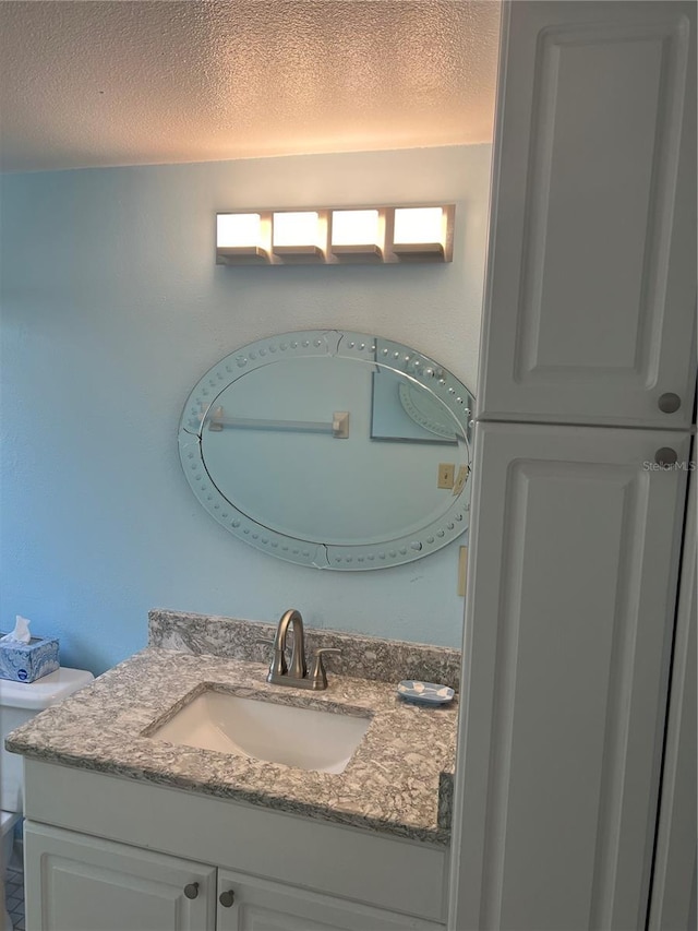 bathroom featuring vanity, a textured ceiling, and toilet