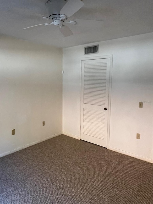 spare room with dark colored carpet and ceiling fan