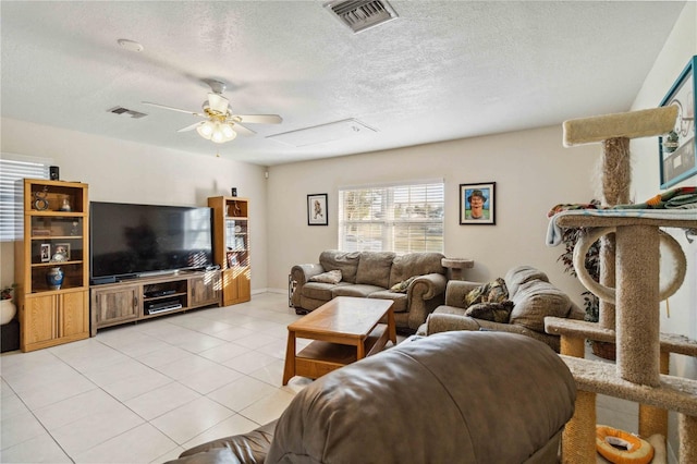 living room with light tile patterned flooring, ceiling fan, and a textured ceiling